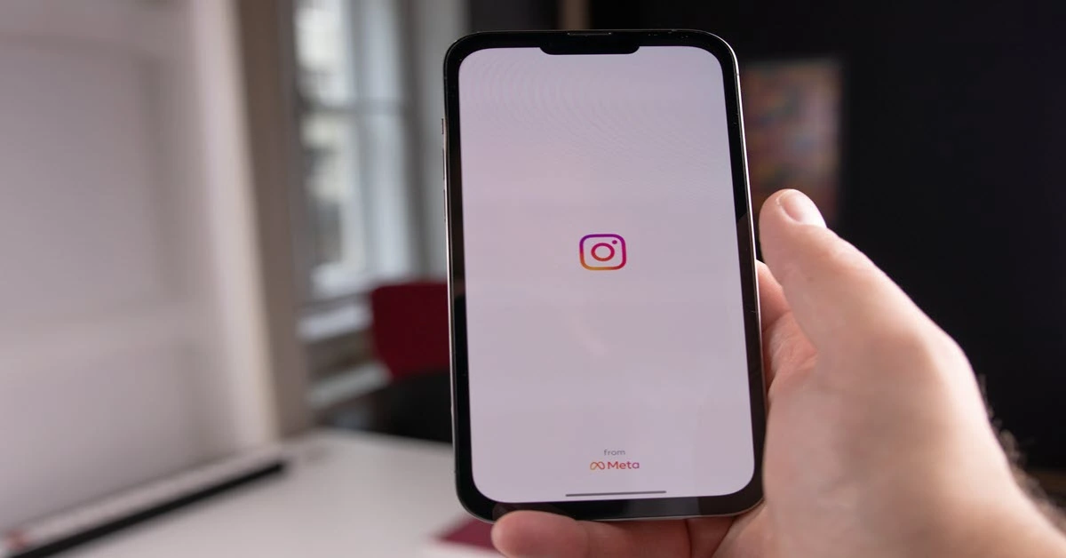  A hand holding a smartphone with the Instagram app open on the screen with a caption reading 'How to use Instagram Quiet Mode'.